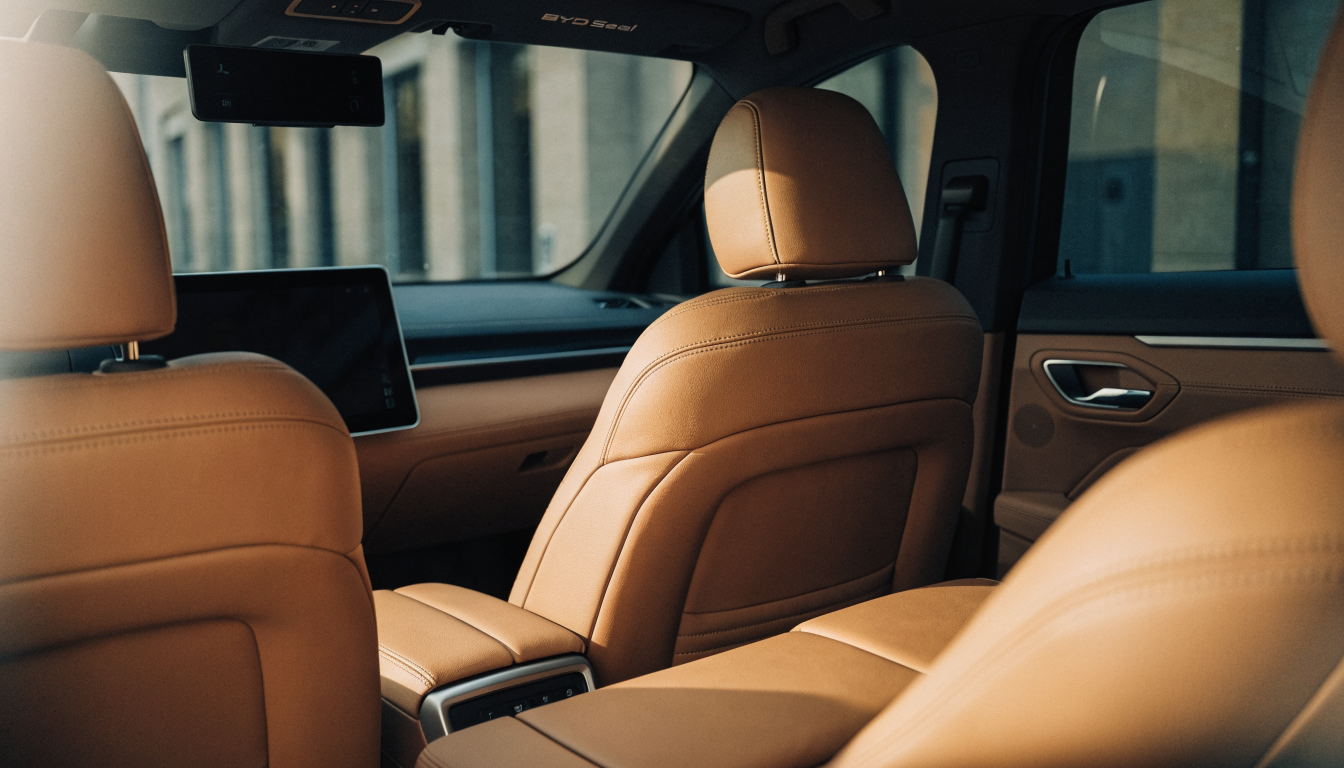 Looking forward from the rear bench of a BYD Seal, light spilling in overhead onto pale leather seats and trim.