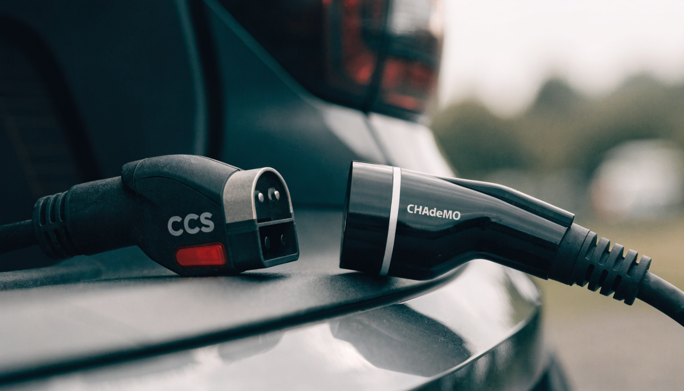 Two mismatched charging cable tips laid out on a car's boot lid, one rounded, one squared off.