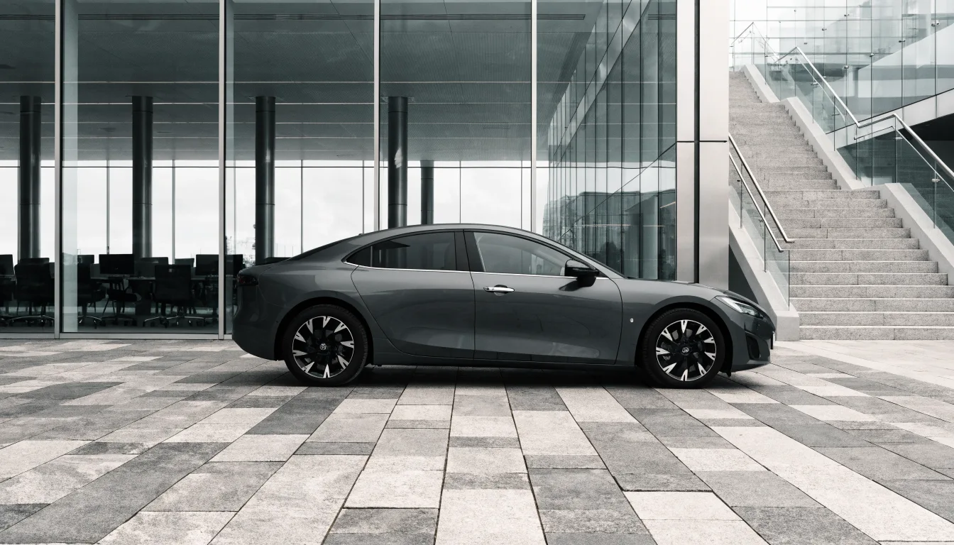 A modern electric company car parked outside a contemporary glass office building.